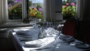 A table set for dining with a view of flowers through the window.