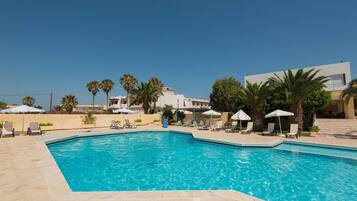 Una piscina al aire libre, sombrillas, sillones reclinables de piscina