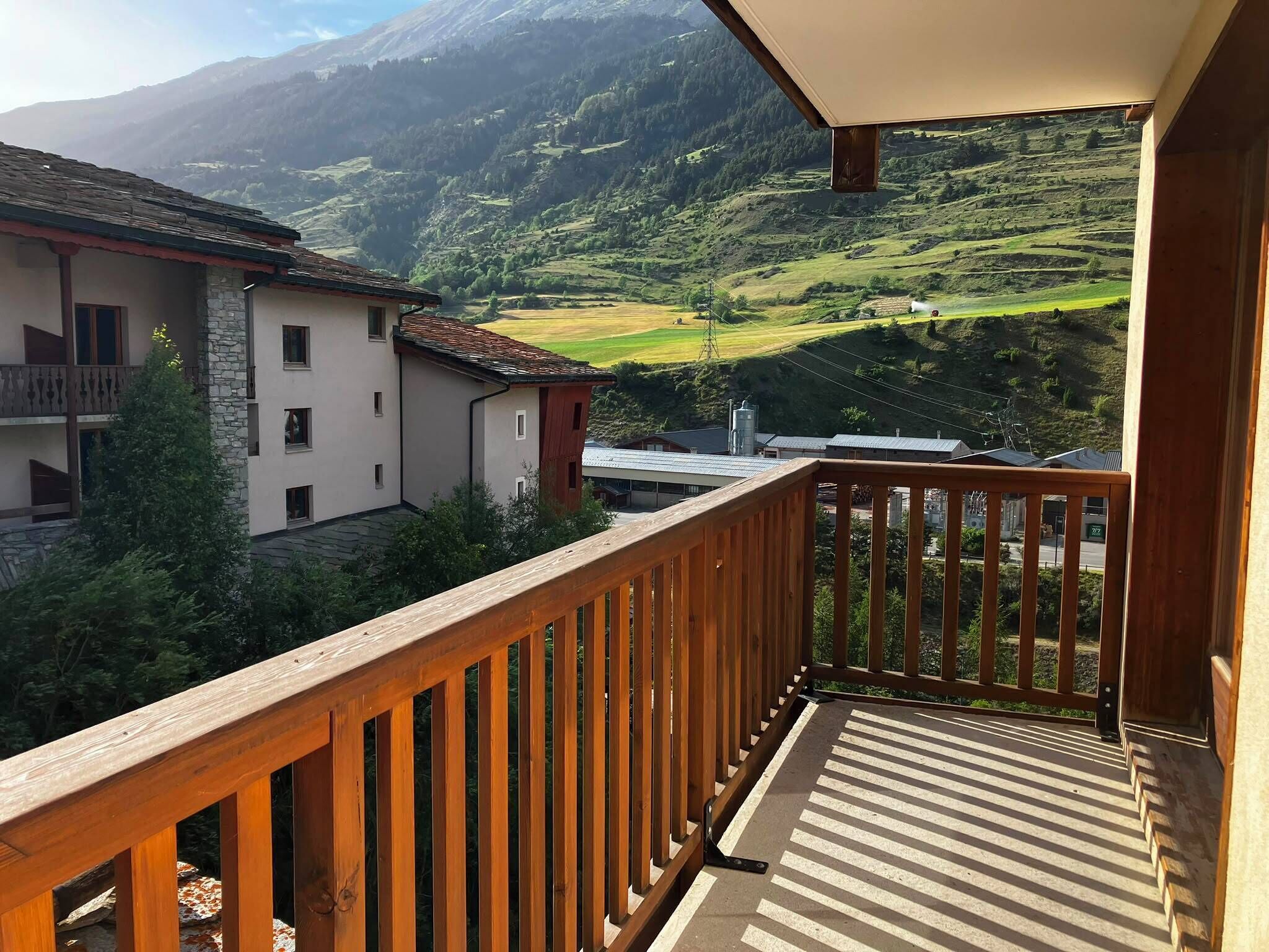 A balcony with a view of a mountainous landscape and buildings.