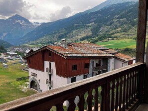 A mountain-view hotel with a balcony overlooking a valley and mountains.