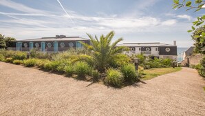 Een gebouw aan de kust met een grindpad en tropische planten.