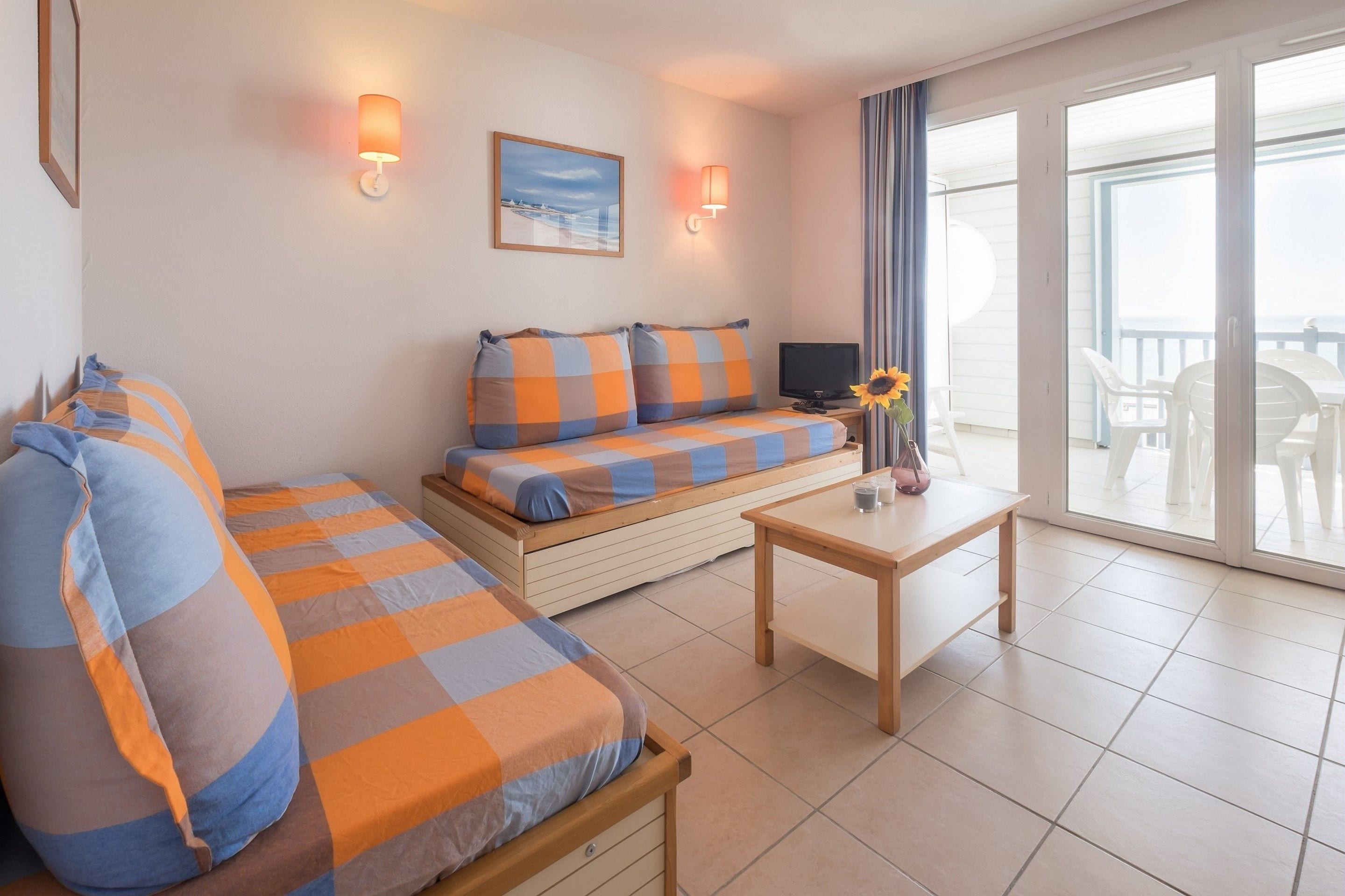 Een gezellige kamer met een bank, een klein tafeltje en een televisie. Er is een balkon met uitzicht.