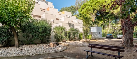 Un parque con un banco, árboles y un edificio al fondo.