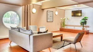 A modern living room with a sofa, armchairs, a coffee table, a TV, and a large window. - Résidence Pierre & Vacances Les Terrasses Du Parc (La Grande-Motte)
