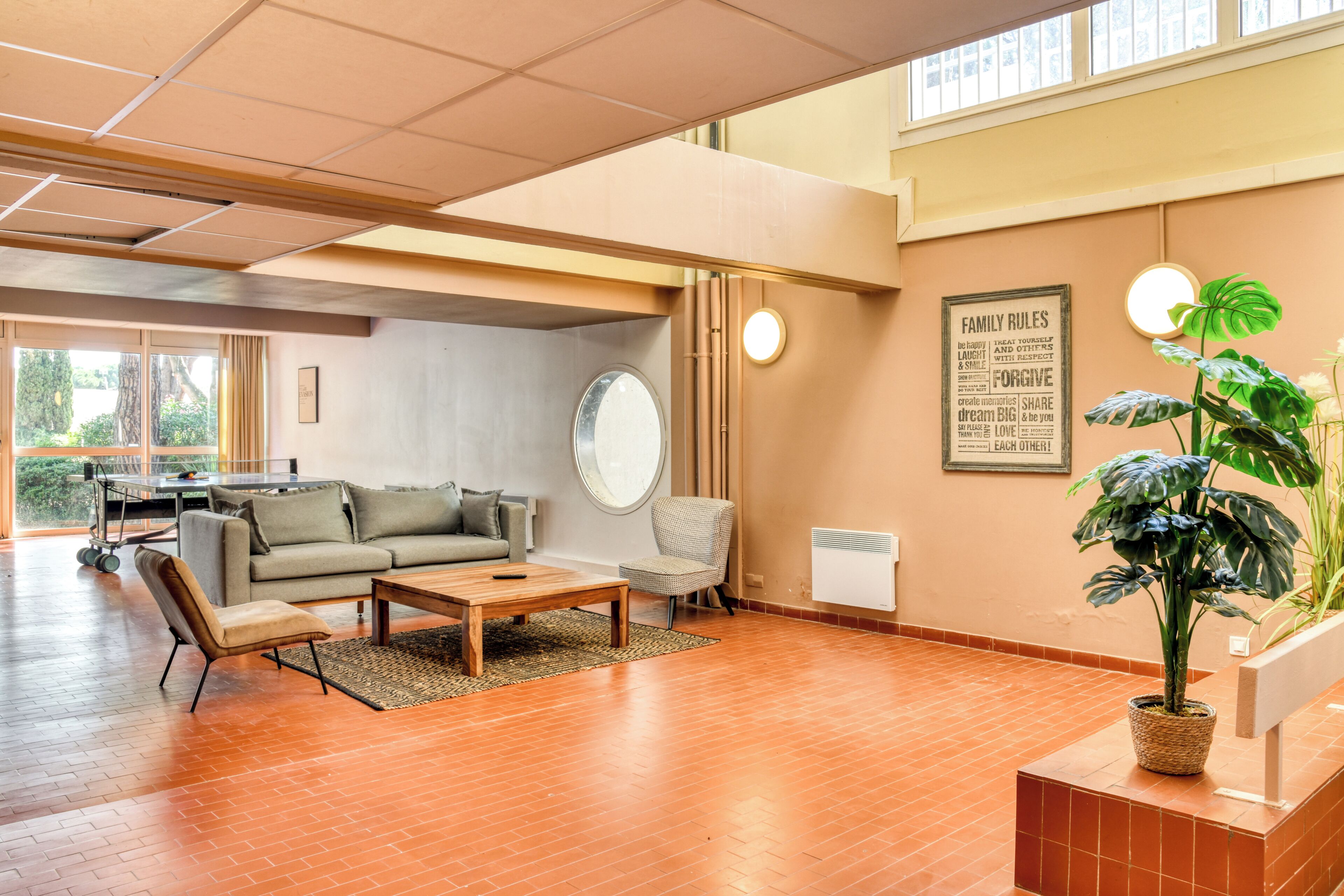 A spacious living room with a sofa, coffee table, and a potted plant.