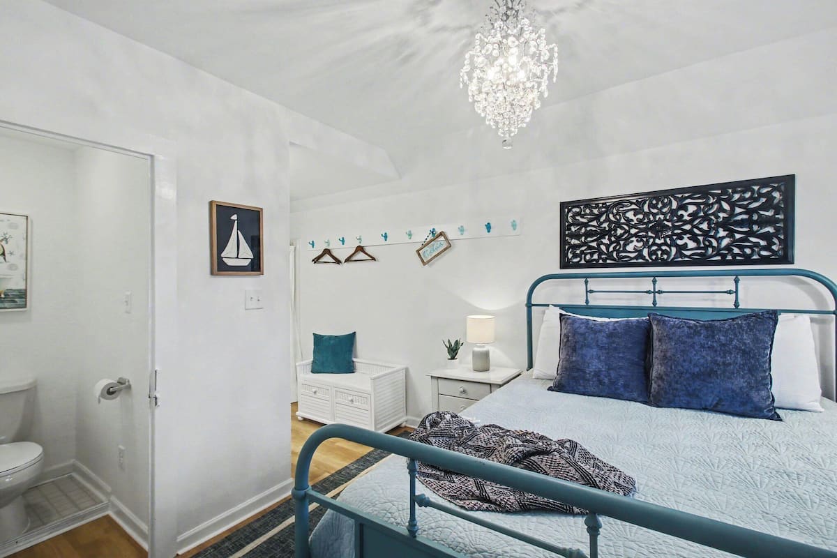 A bedroom with a bed, a nightstand, a dresser, a chandelier, and wall decorations.