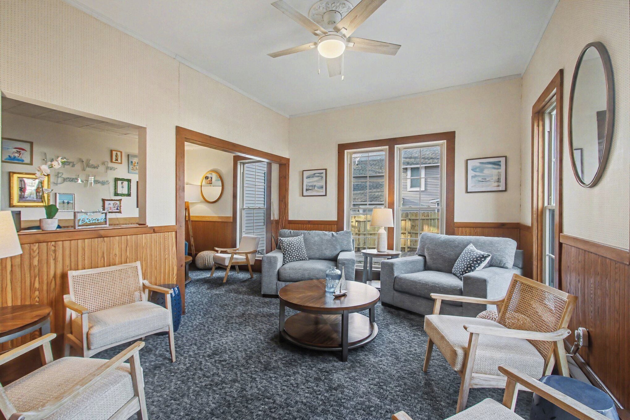 A spacious living room with a ceiling fan, two sofas, a coffee table, and a wooden accent wall.