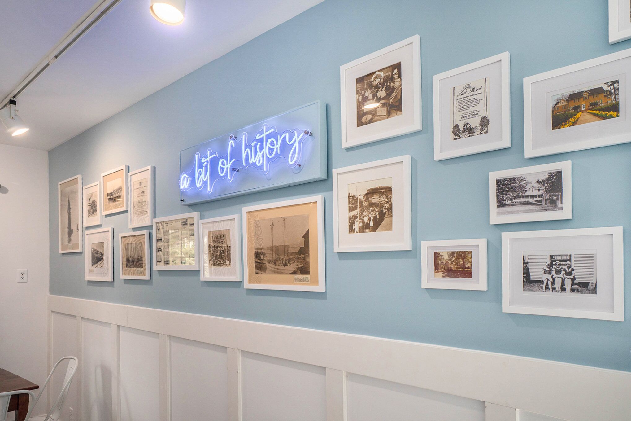 A wall with framed photographs and a neon sign that reads "a bit of history".