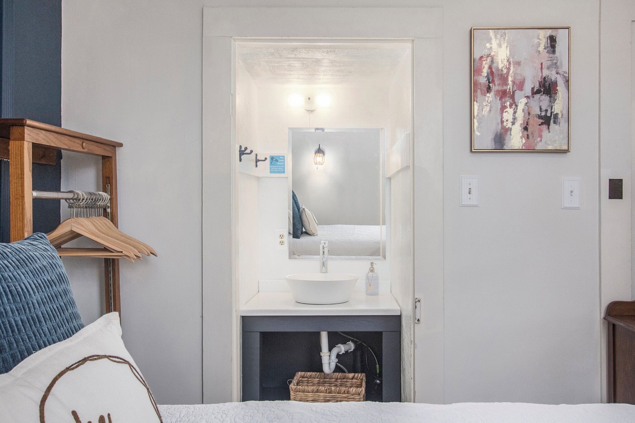 Une salle de bain moderne avec un lavabo blanc, un miroir et un luminaire.