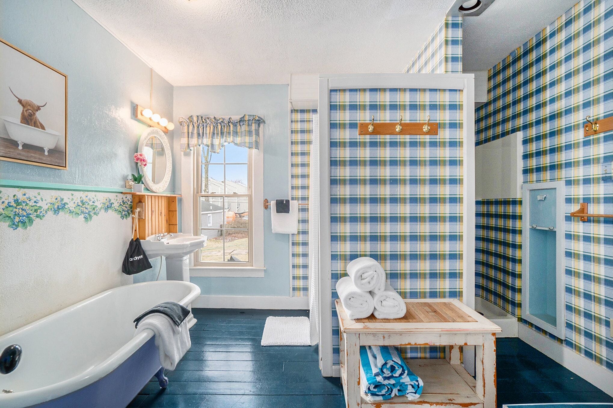 A bathroom with a clawfoot bathtub, a sink, a mirror, and a window.