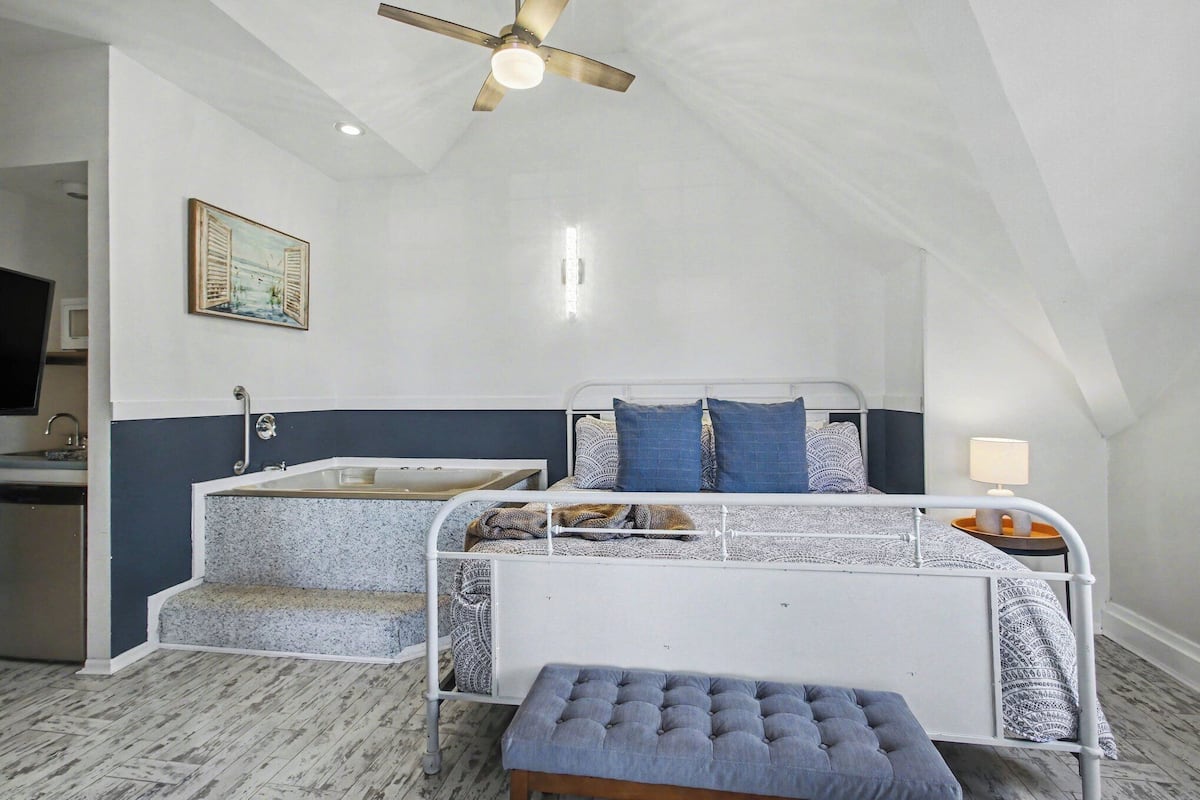 A bedroom with a bed, bedside table, and a small stool.