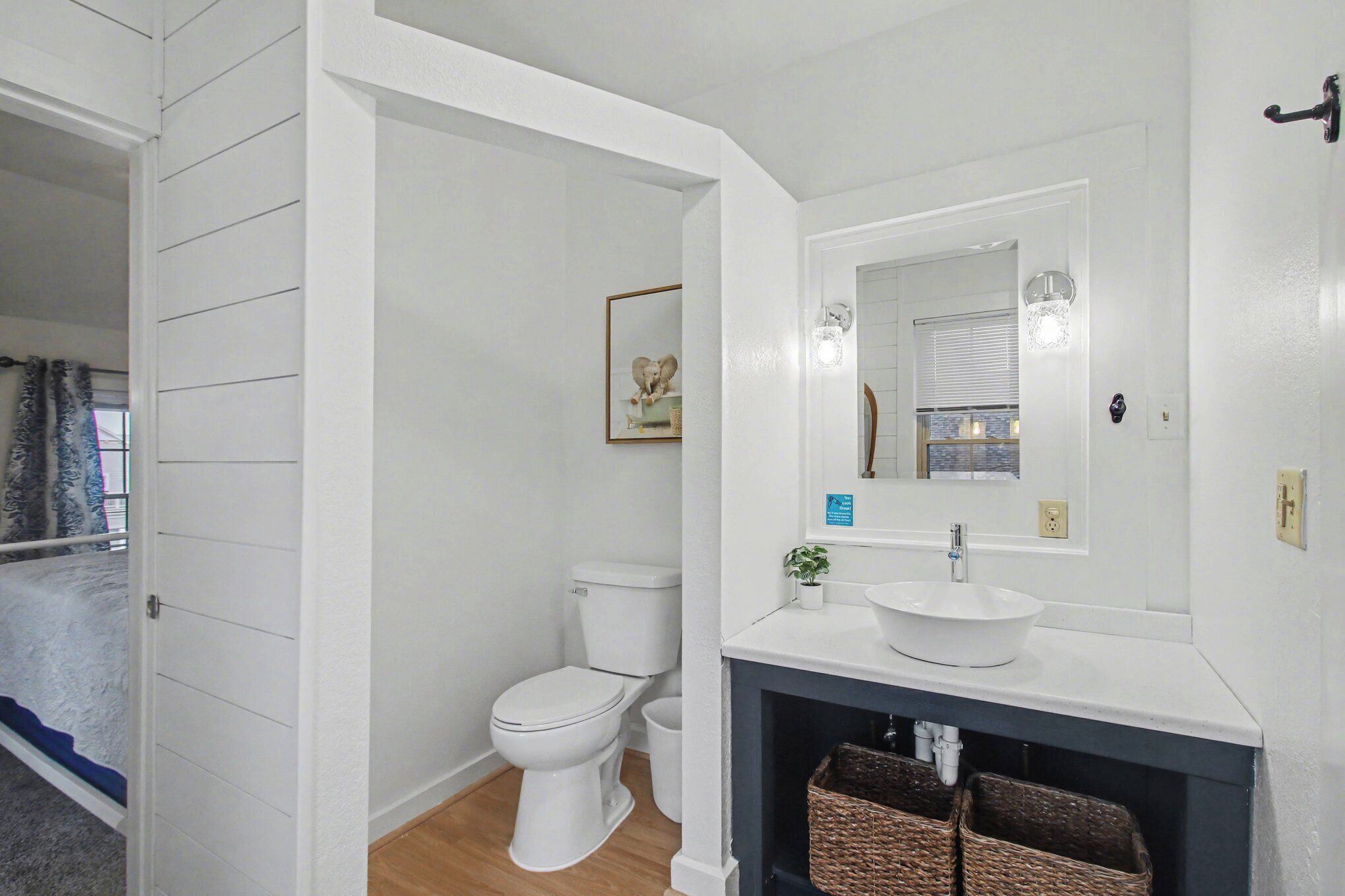 Een badkamer met toilet, wastafel, spiegel en een kleine plant.