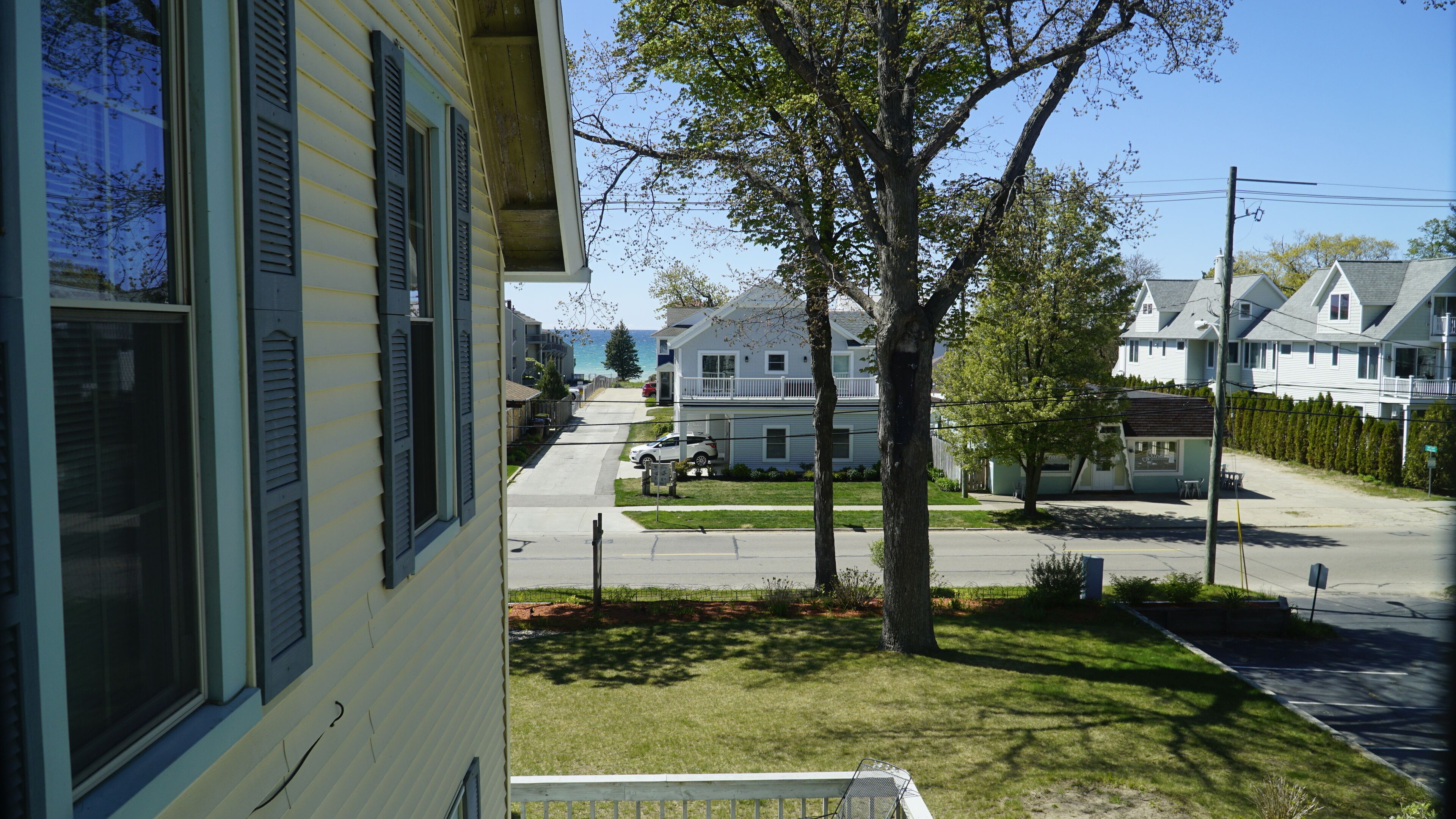 A residential street with houses, a tree, and a clear sky.