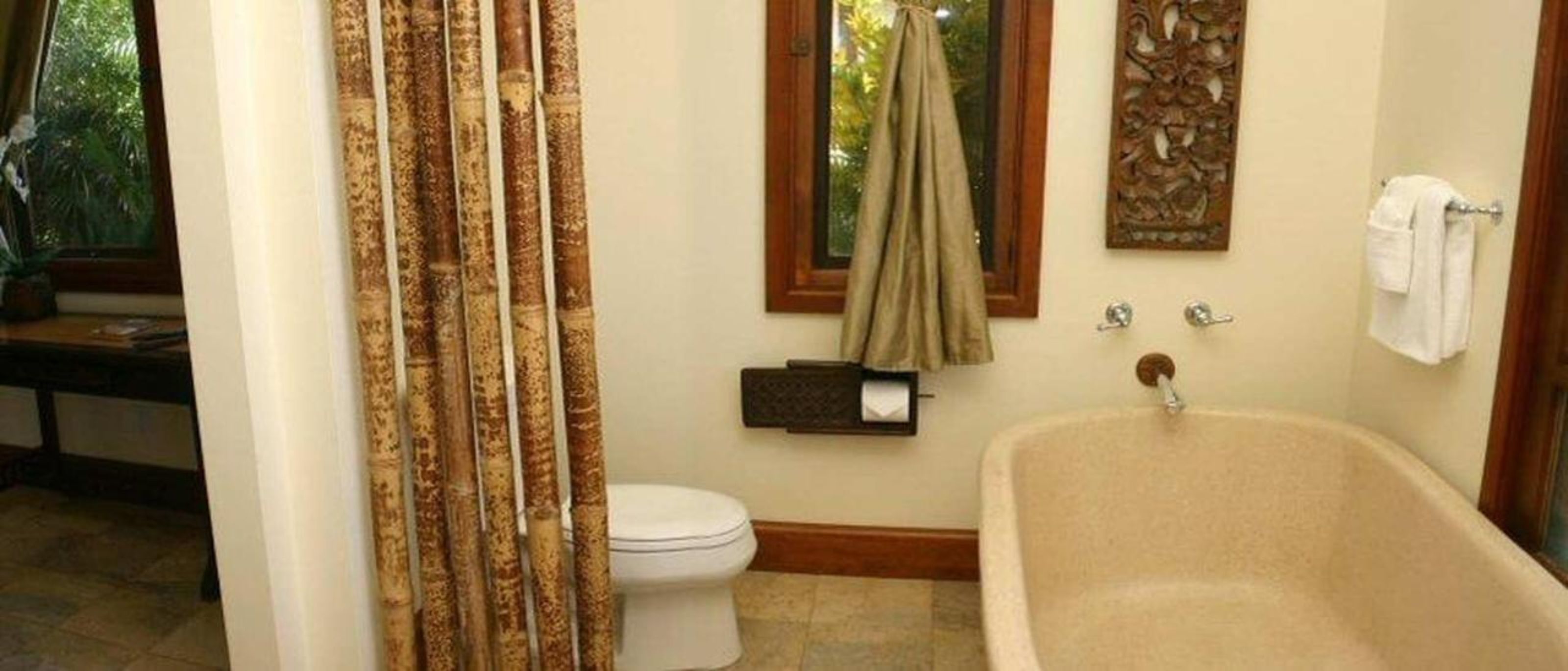 A bathroom with a bathtub, toilet, and a window with a curtain.