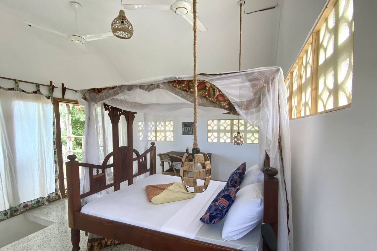Una habitación con cama, lámpara colgante y ventana con vistas.
