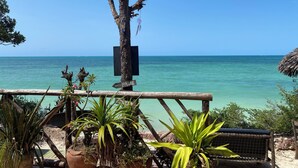 A beach view with a wooden fence, potted plants, and a signboard. - Mbuyuni Beach Village - Bungalows (Jambiani)