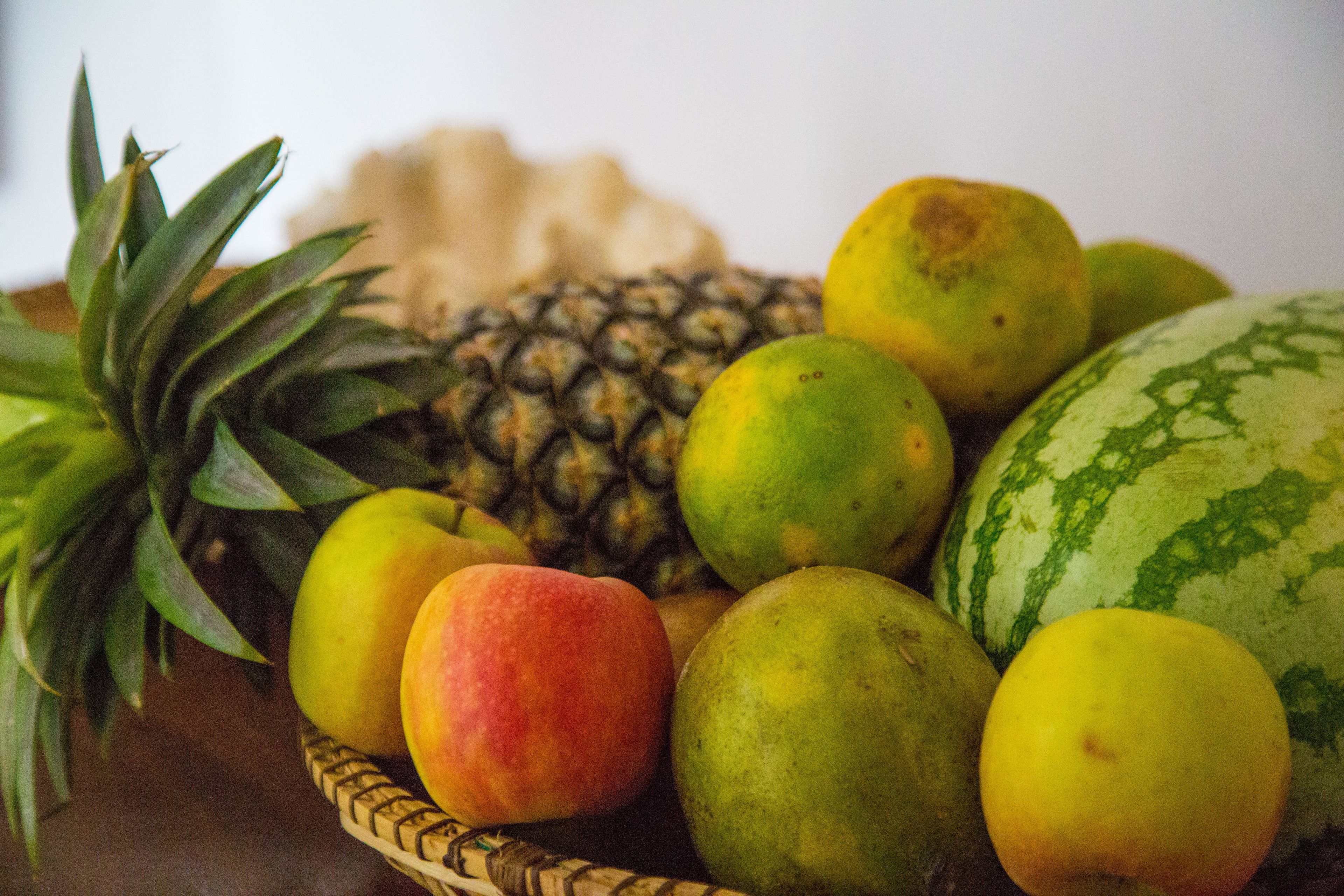 Ein Korb voller Obstsorten, darunter eine Ananas, Mango und Wassermelone.