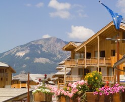 Un chalet en bois doté d’un balcon, entouré de jardinières et avec une vue sur les montagnes en toile de fond.