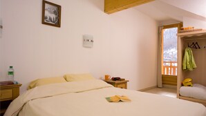 A bedroom with a bed, a bedside table, a nightstand, a window with a view, and a coat rack. - Madame Vacances - Residence Les Balcons des Airelles (Les Orres)