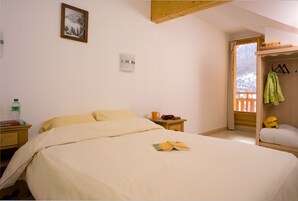 Une chambre à coucher comprenant un lit, une table de chevet, une commode, une fenêtre avec vue et un porte-manteau.