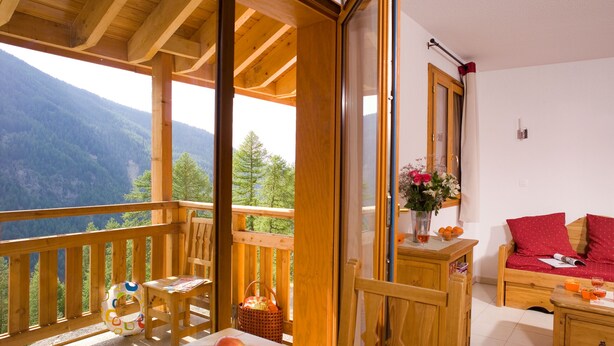 A wooden balcony with a table, chairs, and a basket of fruit. - Madame Vacances - Residence Les Balcons des Airelles (Les Orres)