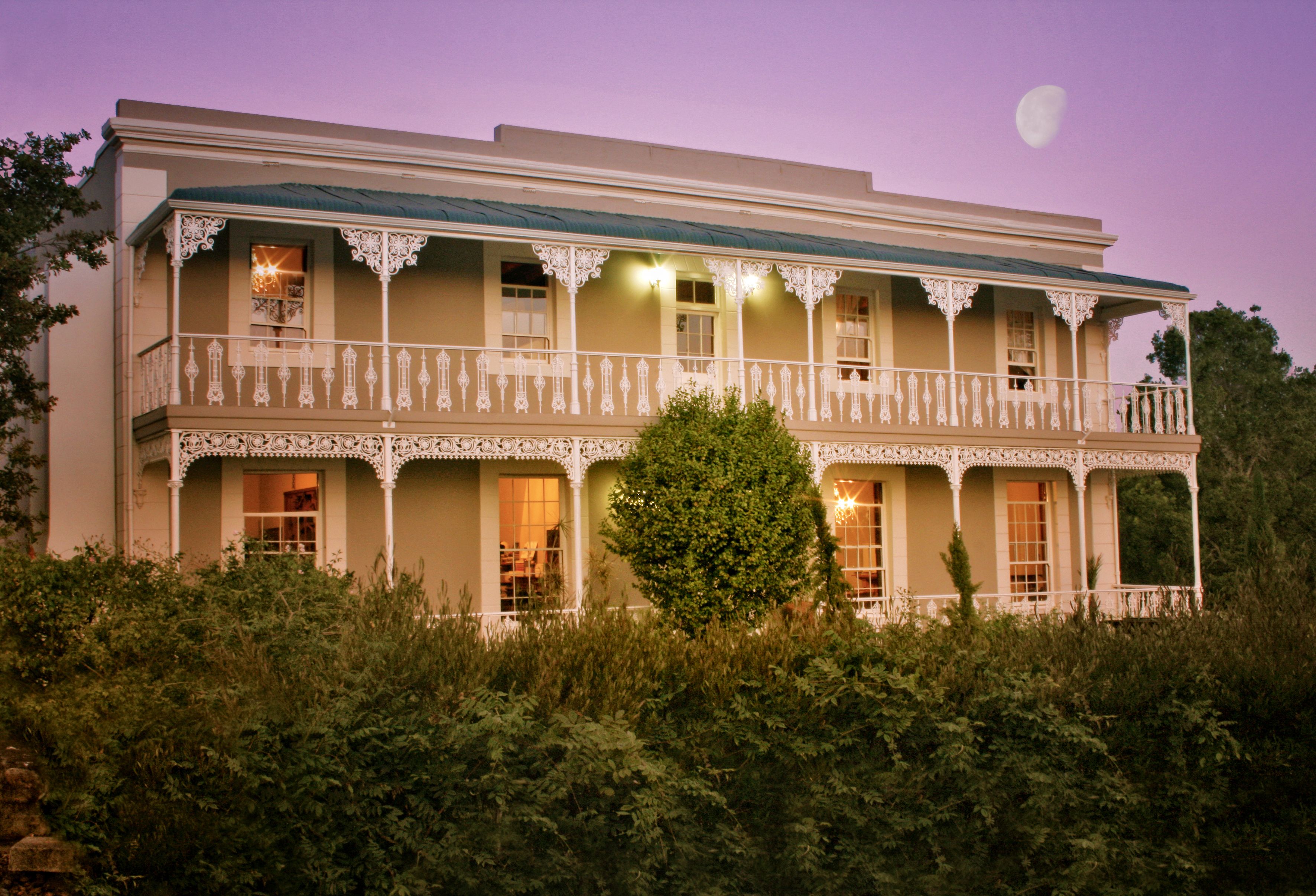 A two-story building with a balcony and a tree in front.