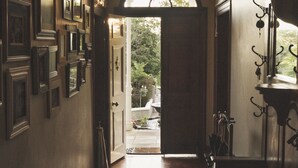 A hallway with wooden flooring, a large arched doorway leading outside, and a hanging light fixture. - Schoone Oordt Country House (Swellendam)