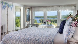 Une chambre avec un grand lit, une vue sur un lac et une table décorée de fleurs.