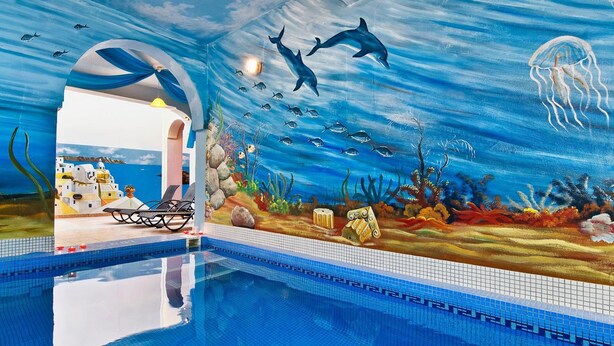 Una piscina interior con un mural de escena submarina, incluyendo delfines, peces y una medusa.