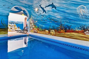 An indoor swimming pool with a mural of an underwater scene, including dolphins, fish, and a jellyfish. - Petros Villa (Santorini)
