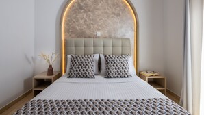 Un dormitorio moderno con una cama grande, cabecera de diseño único y mesitas de noche con lámparas.
