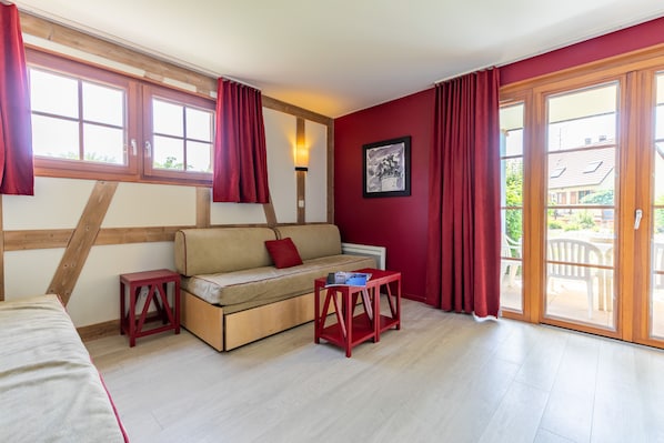 A room with a sofa, a small table, and a window with curtains.