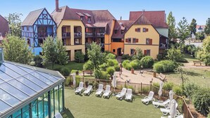 A courtyard with a pool, sun loungers, and a glass greenhouse. - Pierre & Vacances Résidence Le Clos d'Eguisheim (Eguisheim)