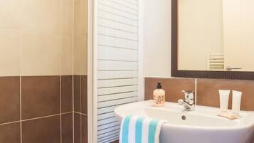 A bathroom with a shower, sink, and mirror.