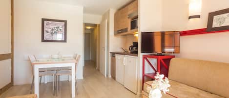 Un espace de vie compact comprenant un coin repas, une kitchenette et un canapé.