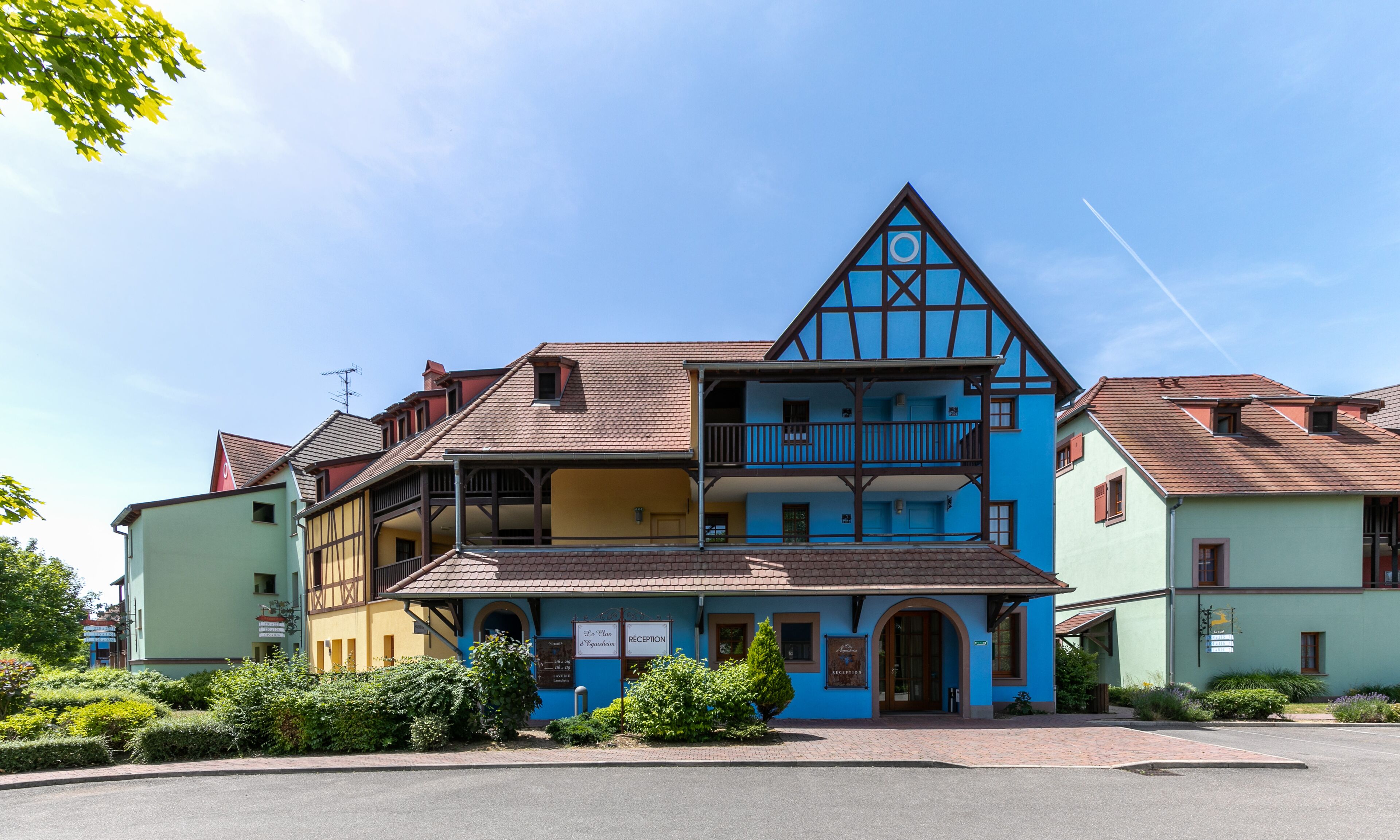 Un edificio europeo tradizionale con un tetto a capanna sporgente, un balcone e un cartello che indica la reception.
