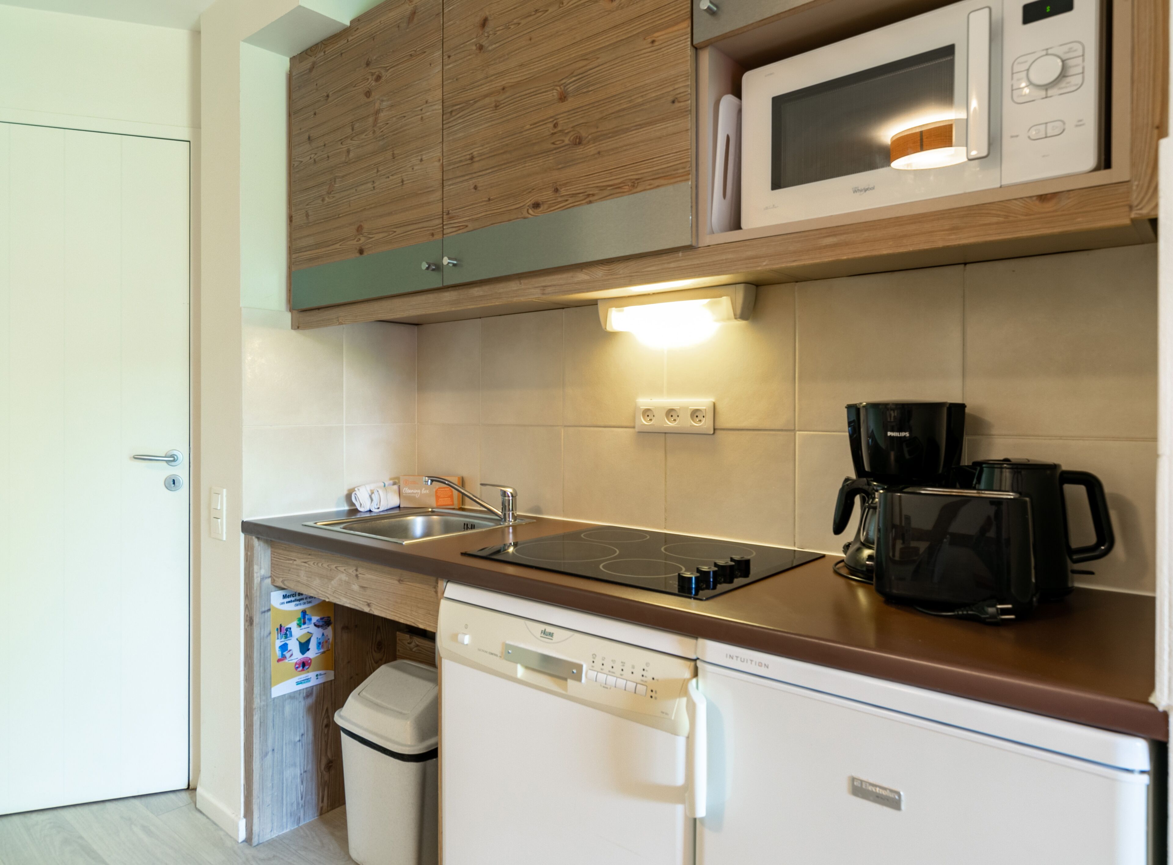 A compact kitchen with a microwave, coffee maker, and dishwasher.
