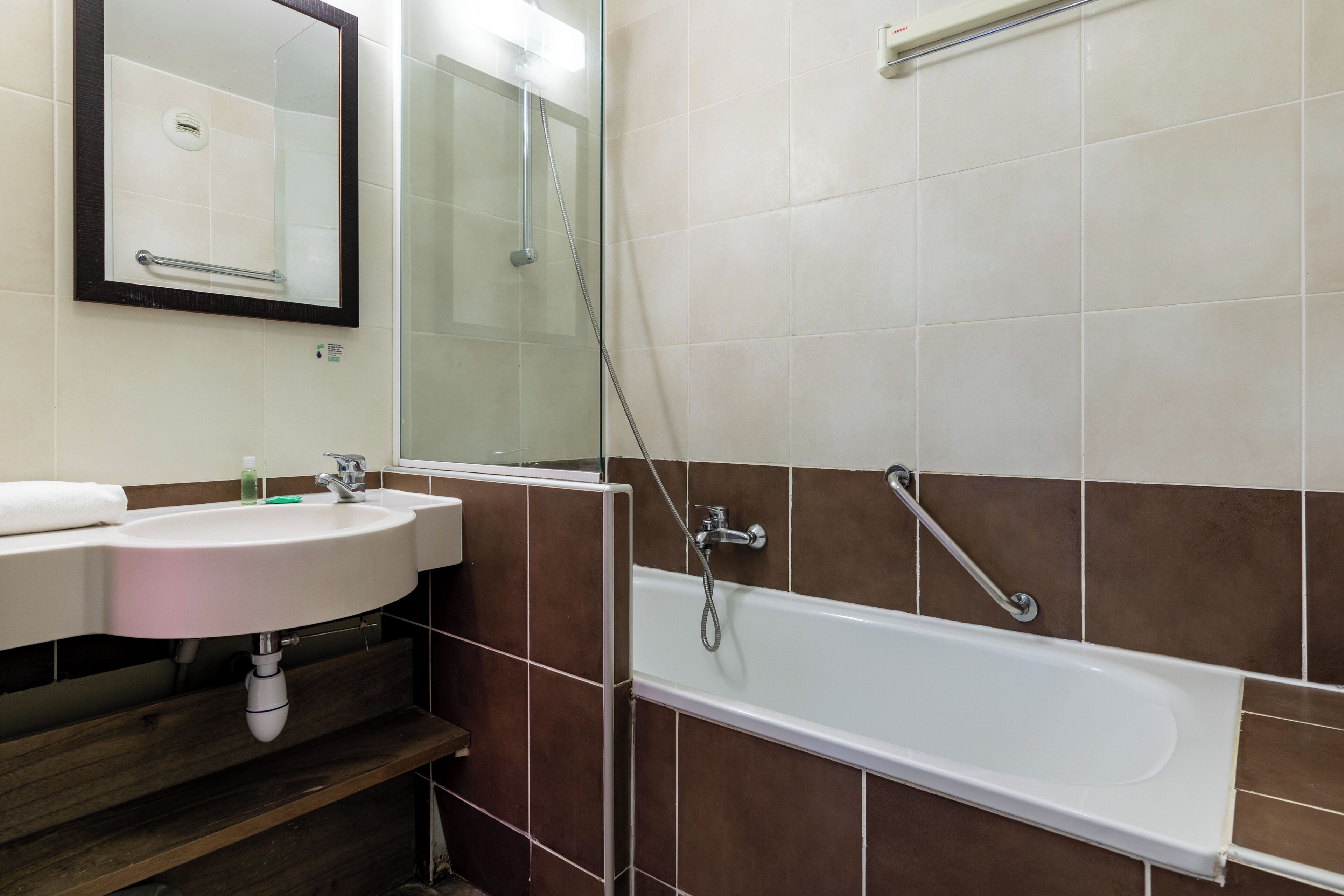 A bathroom with a sink, mirror, and bathtub.
