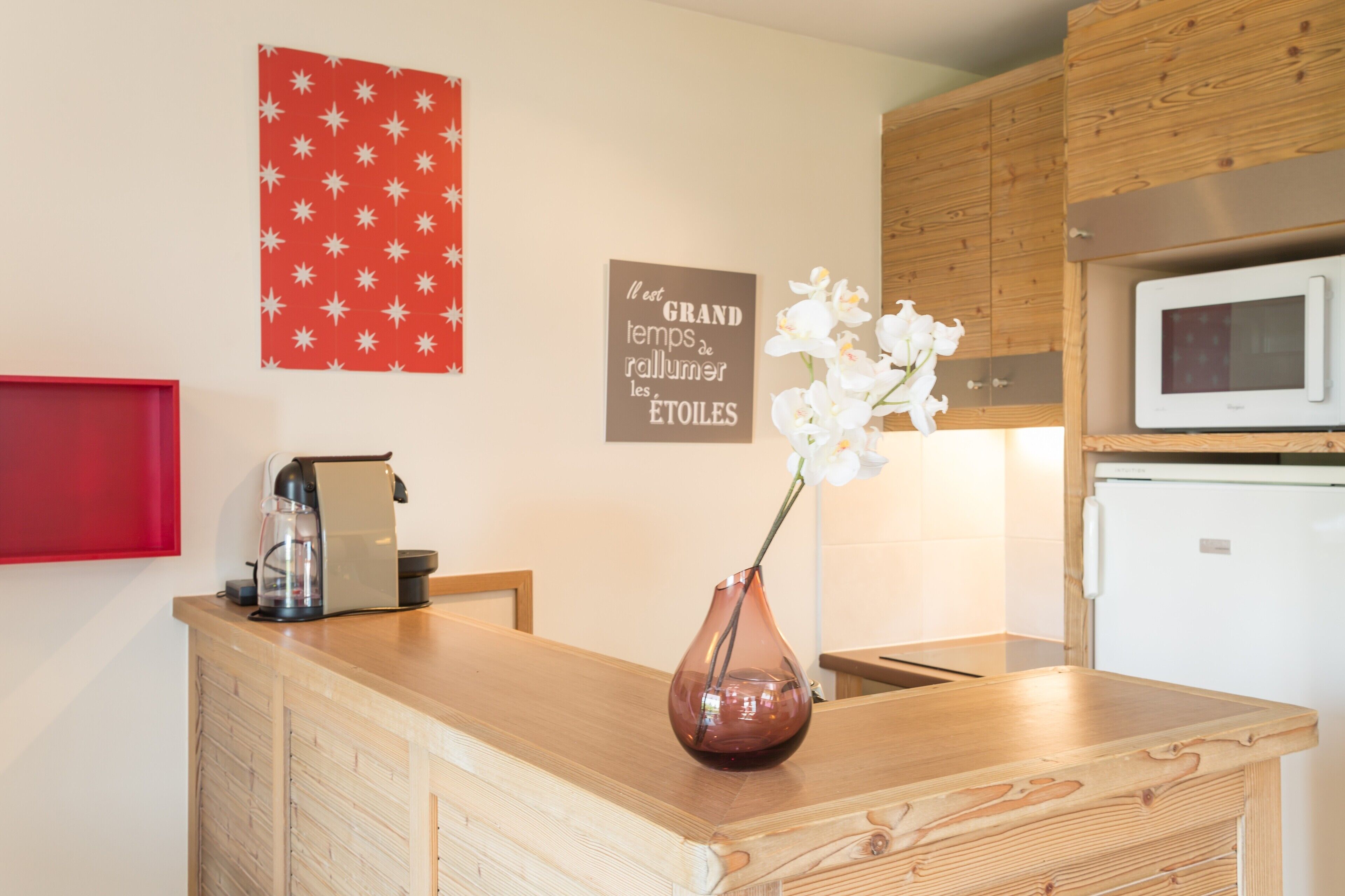 A kitchen with wooden cabinets, a microwave, and a coffee machine on the counter.