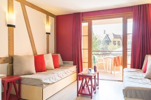 A room with a sofa, a small table, and a view of the outside. - Pierre & Vacances Résidence Le Clos d'Eguisheim (Eguisheim)