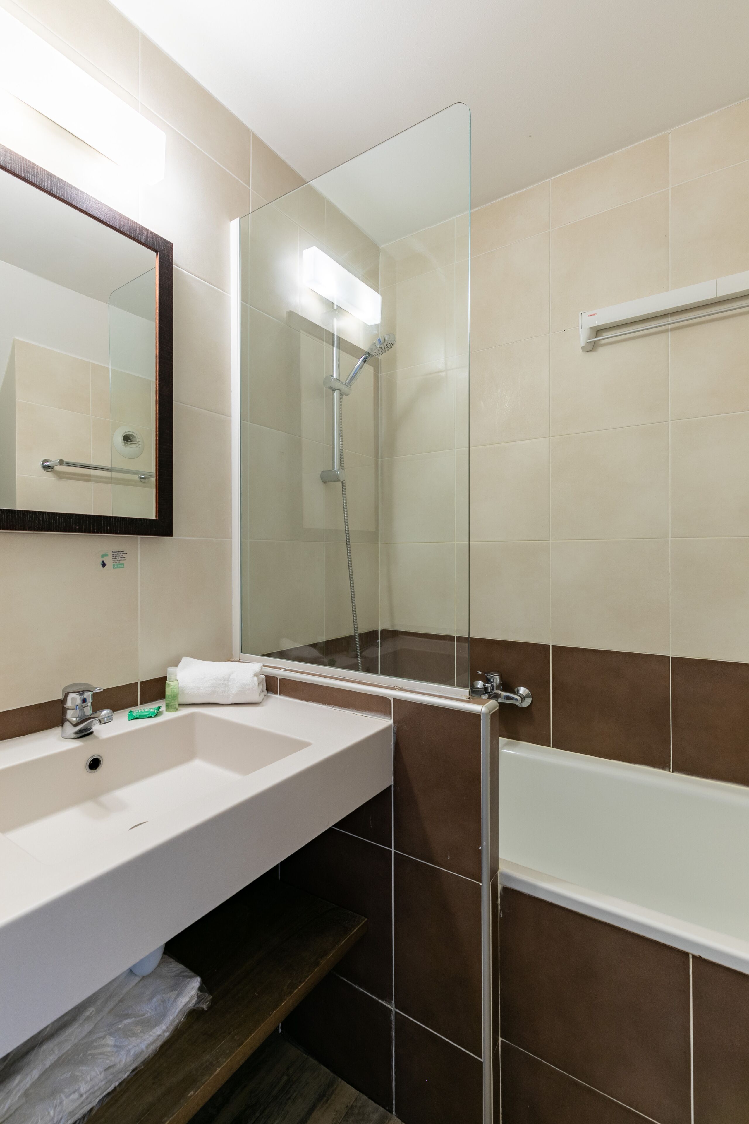 A modern bathroom with a white sink, a mirror, a glass shower enclosure, and a bathtub.