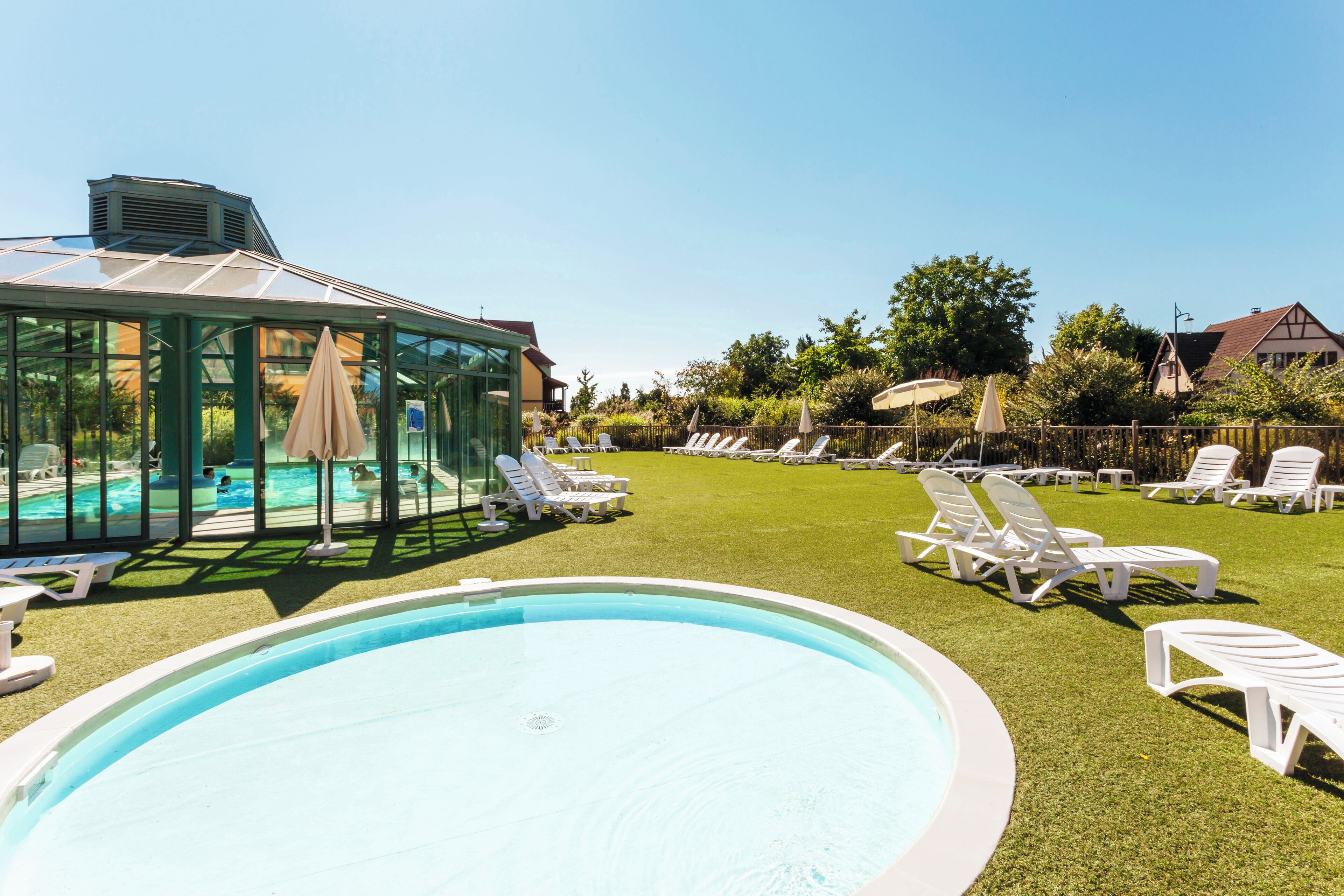 A swimming pool with lounge chairs and a glass-enclosed structure.