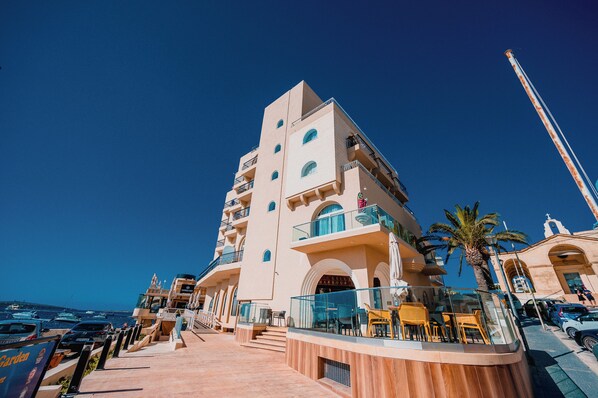 Un hotel de varios pisos con balcones, una zona de piscina y vistas al mar.