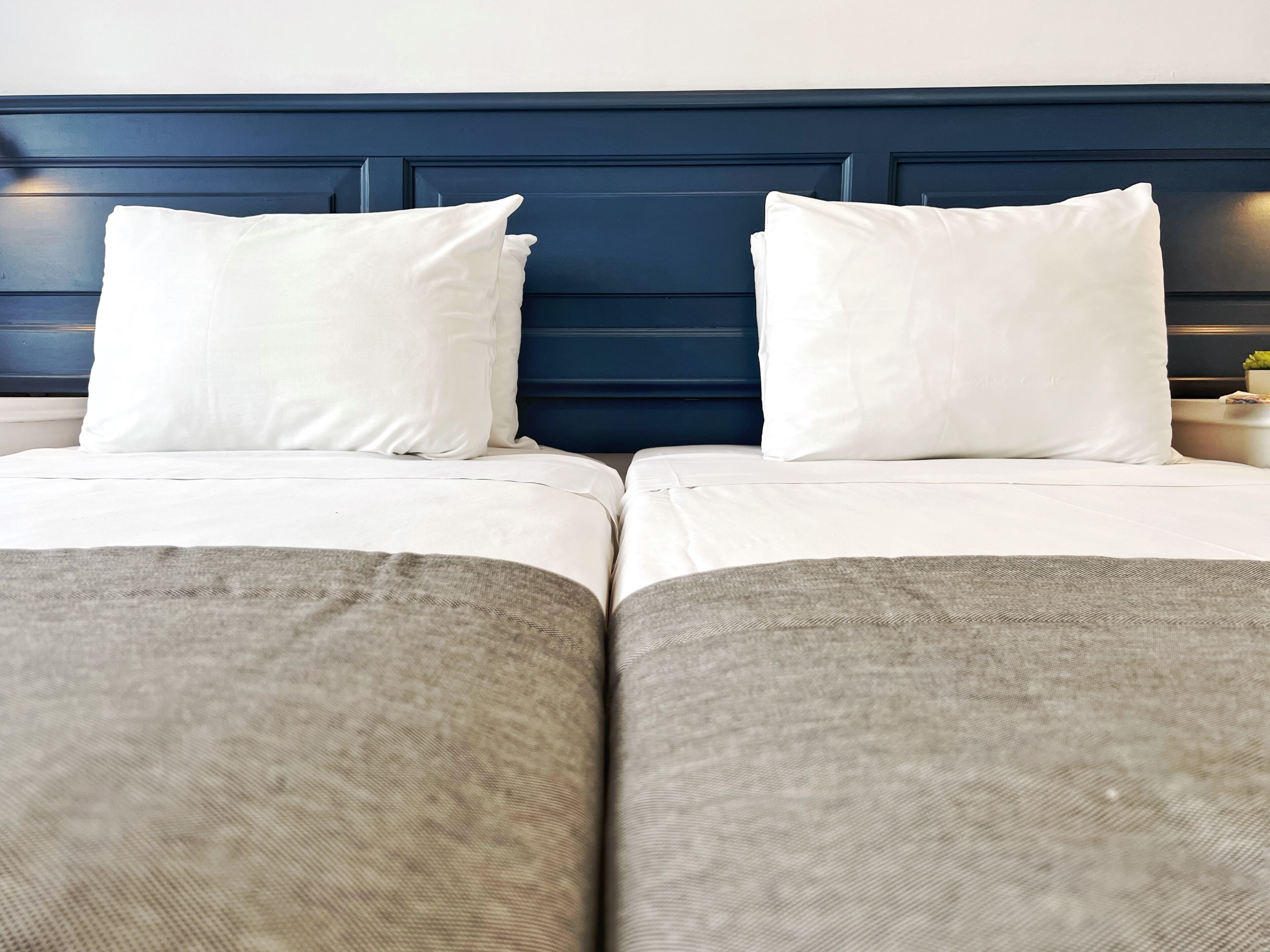 Ein Doppelbett mit weißen Bettwäsche und einem dunkelblauen Kopfteil.