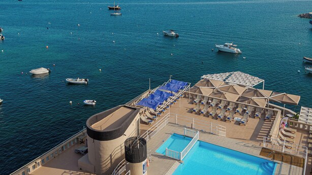 A pool area with lounge chairs and a view of the sea. - Gillieru Harbour Hotel (St. Paul's Bay)