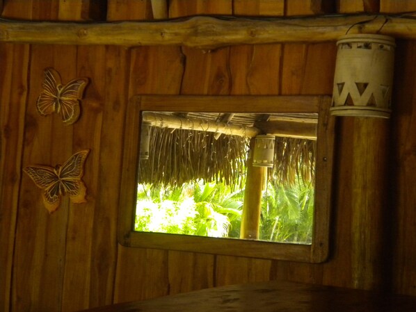 Una pared de madera con una ventana, techo de paja y un poste de metal.