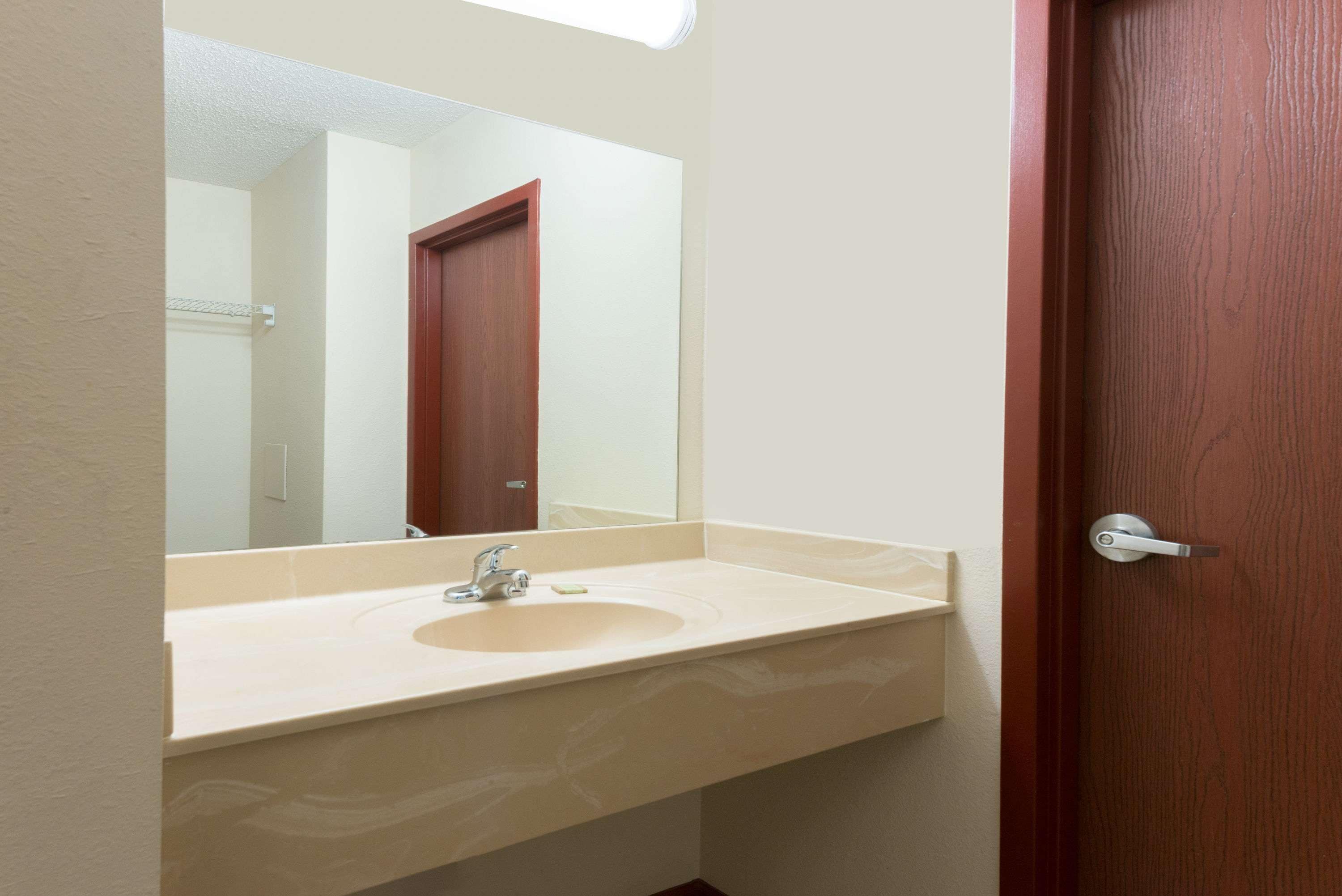 Een badkamer met een beige wastafel, een spiegel en een houten deur.