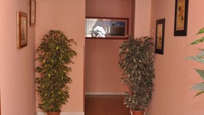A hallway with wooden flooring, two potted plants, and framed artwork on the walls. - Gialel Guesthouse (Rome)
