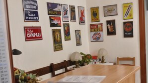 A conference room with a long wooden table, several chairs, and a wall decorated with vintage posters. - Gialel Guesthouse (Rome)