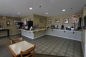 A clean, well-lit restaurant with a counter, chairs, and various food and drink displays.
